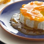 Slice of lemon meringue pie with golden-brown meringue topping and custard filling on a blue and white plate.