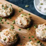 Toasted bread slices topped with white cheese spread and garnished with pumpkin seeds and chives on a wooden board.