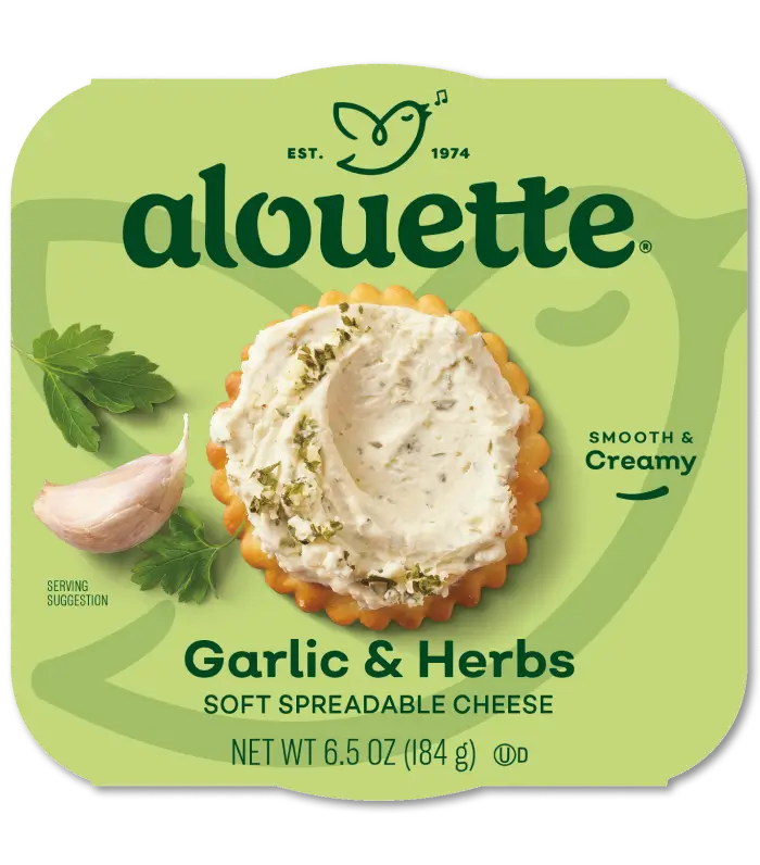 Alouette Garlic & Herbs soft spreadable cheese package showing creamy cheese spread on a cracker with fresh herbs, 6.5 oz container.