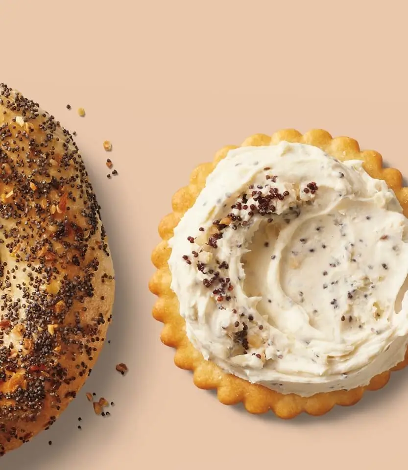 Two pastries on beige background: left shows a seeded bagel with poppy and sesame seeds; right displays a cream-filled tart with whipped frosting and seed garnish.