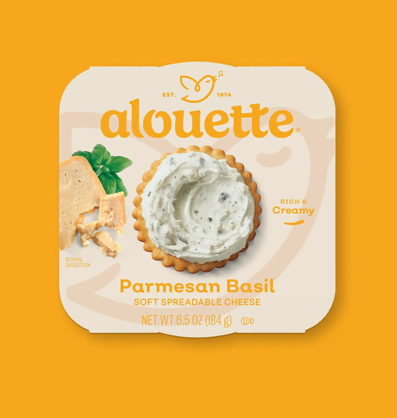 Alouette Parmesan Basil soft spreadable cheese package on yellow background, showing creamy cheese on a cracker with fresh basil leaf.